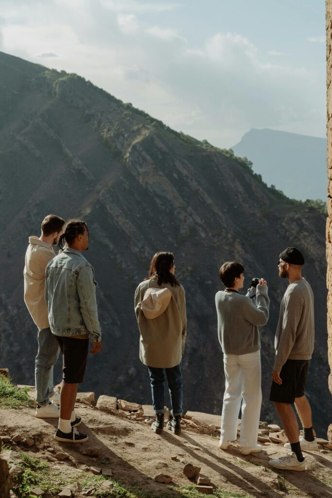 pexels photo 9943049 9943049 A group of five friends enjoying a scenic outdoor adventure on a mountain cliff.